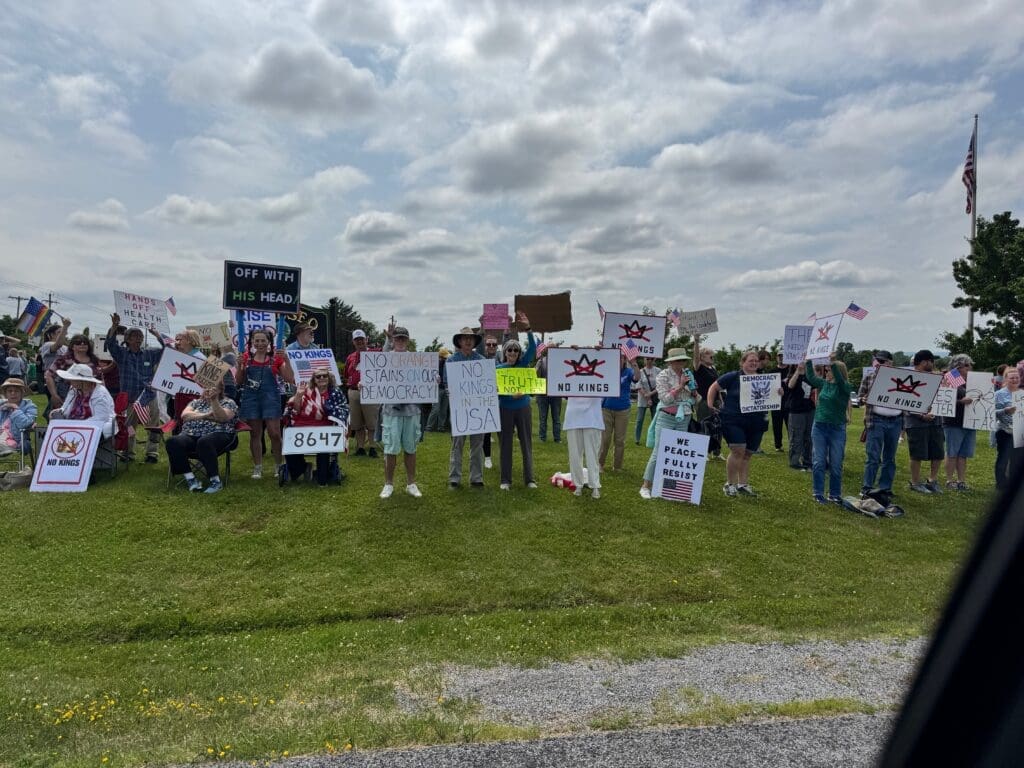 Protesters holding signs on a grassy area.