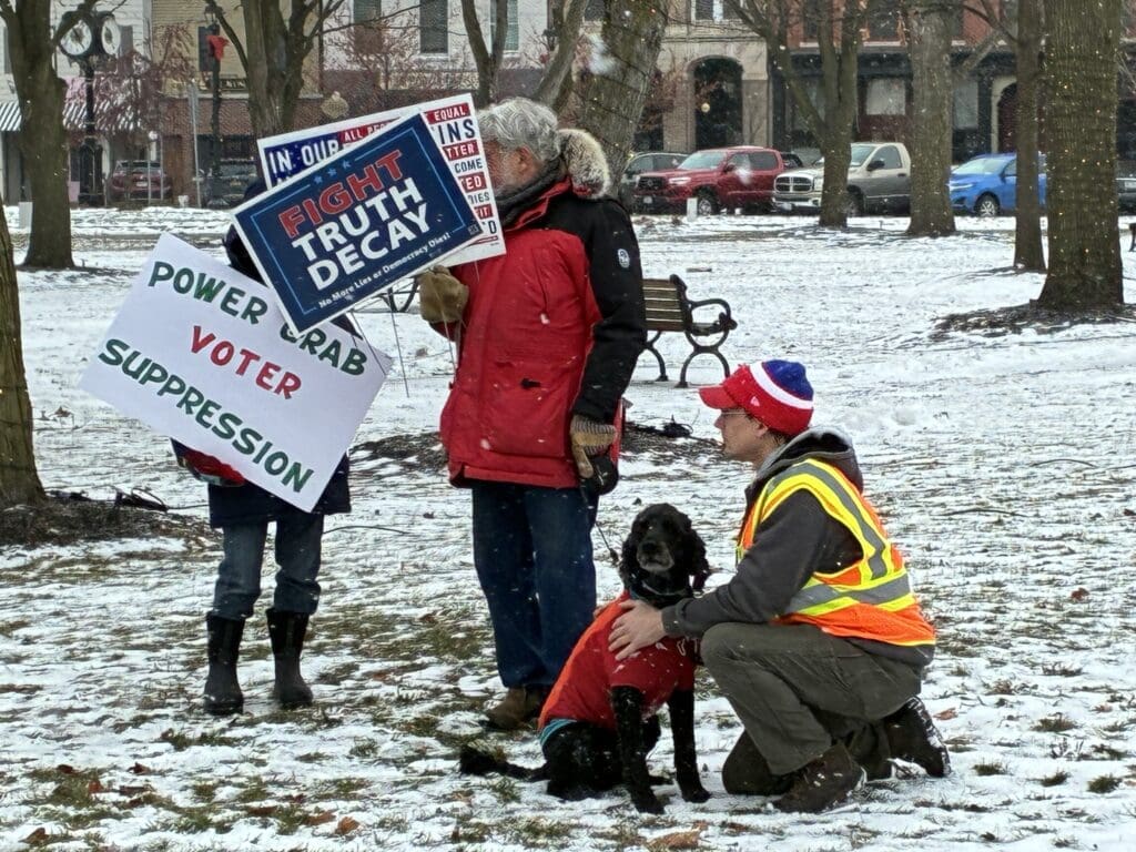 Protesters holding signs in snowy park.