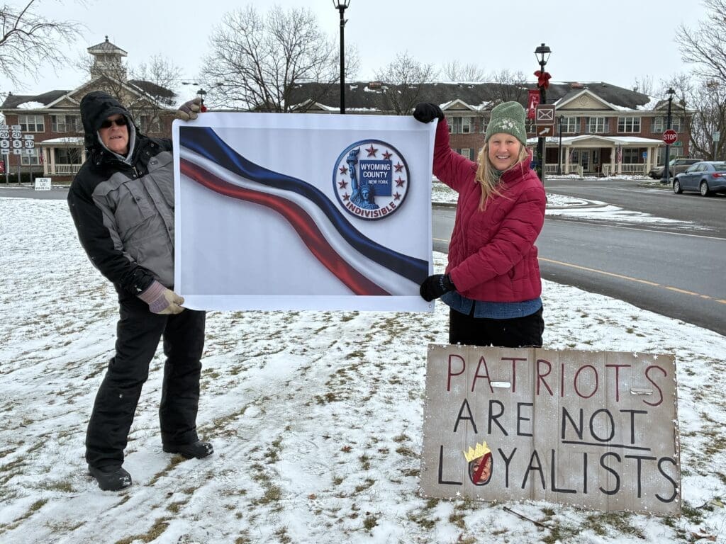 Two people holding signs in snowy area.
