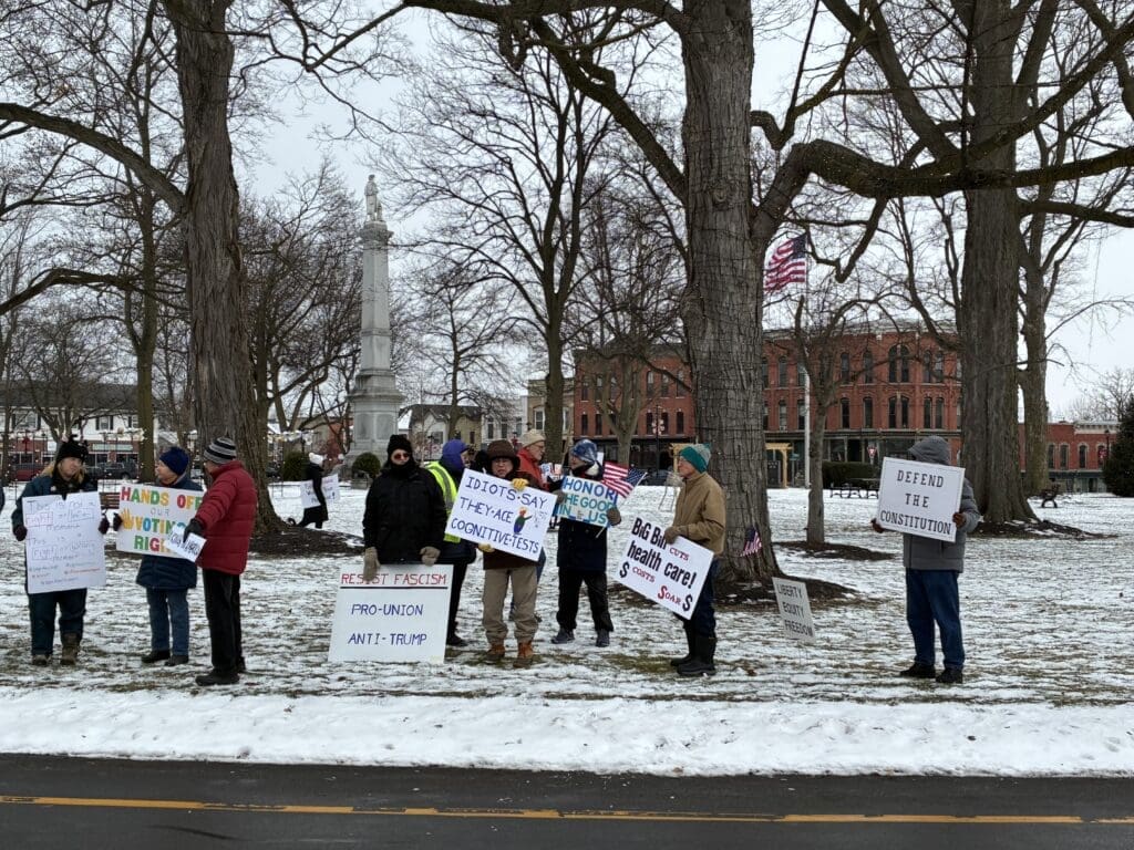 Protesters holding signs in snowy park.