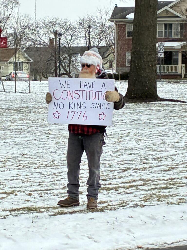 Snowy protester holding sign supporting U.S. Constitution.
