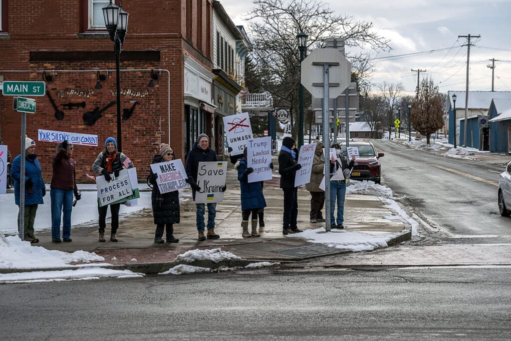 Protesters holding signs on snowy small-town corner