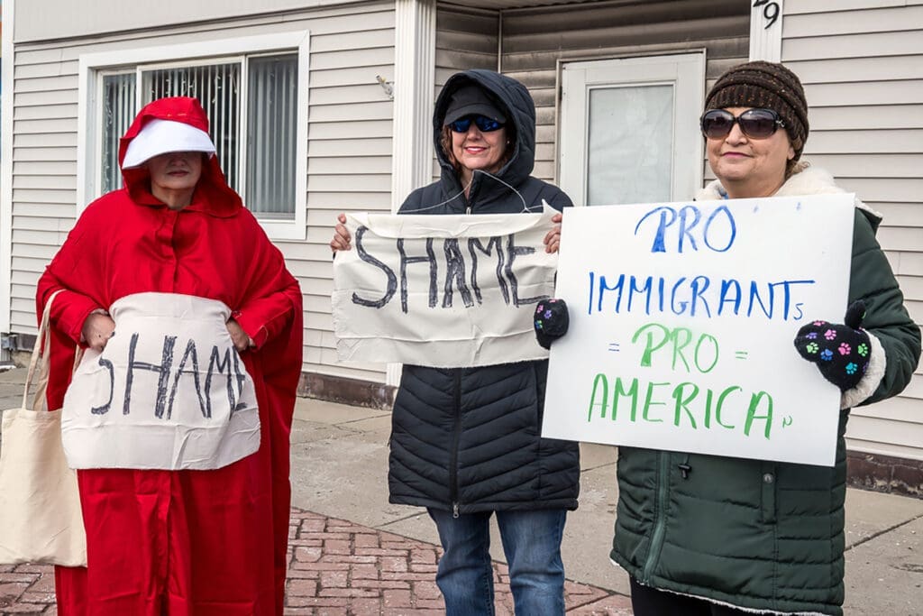 Women holding protest signs outside building