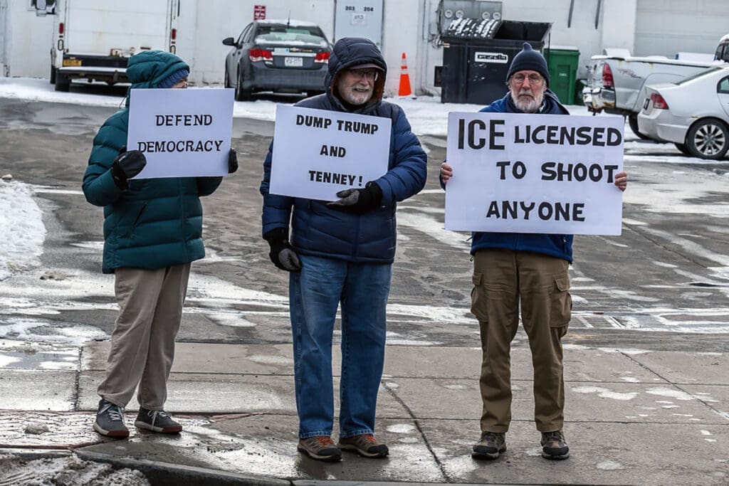 Three protesters holding political signs in winter street