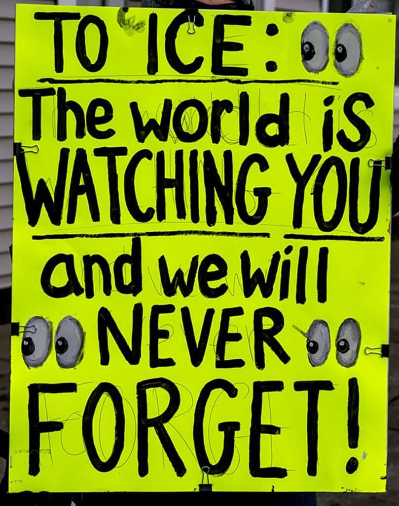 Neon protest sign criticizing ICE with watchful eyes
