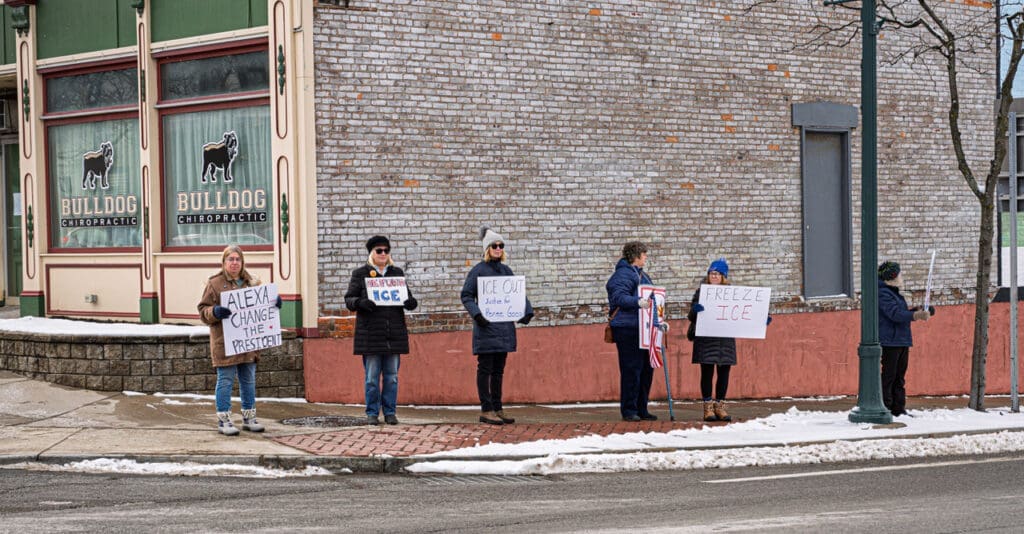 Protesters holding signs on snowy sidewalk.