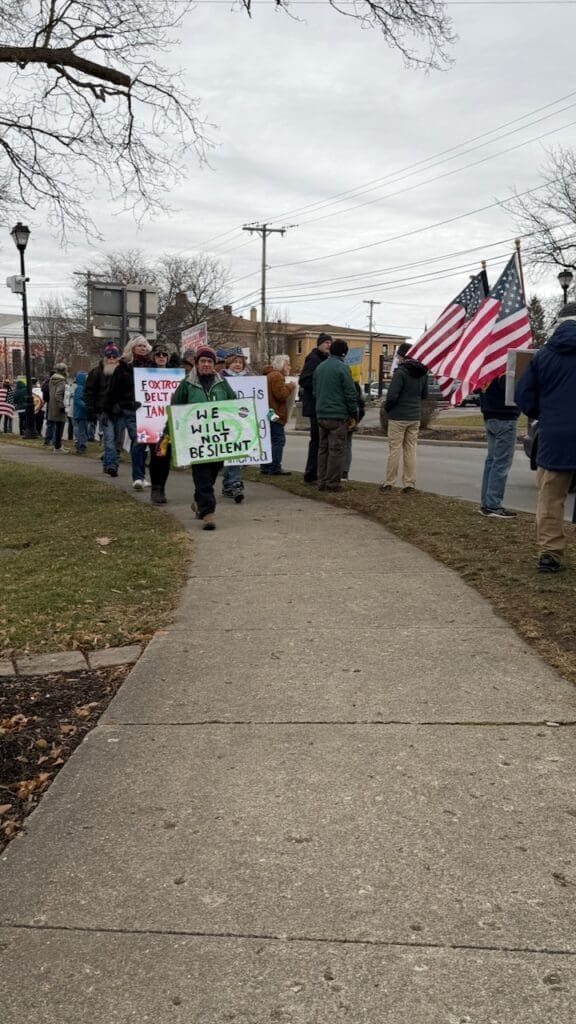 Protesters with signs and American flags marching.