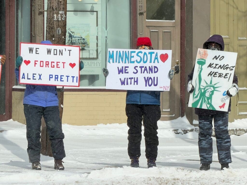 People holding protest signs in snowy street.