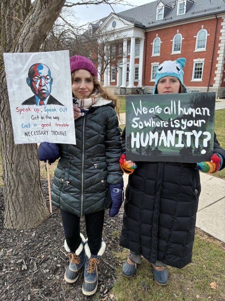 Two women holding protest signs outdoors