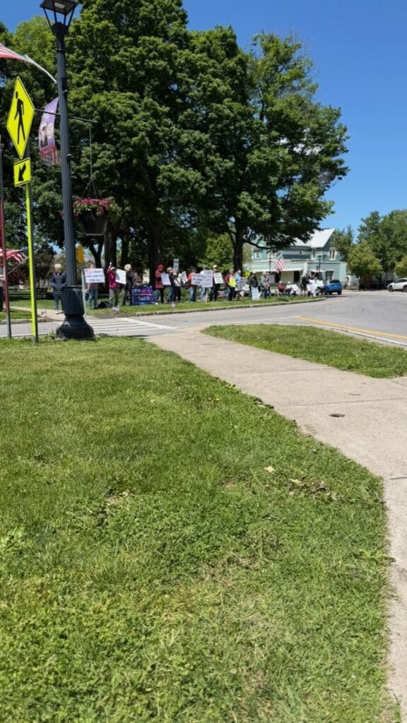 People holding protest signs on small-town street corner