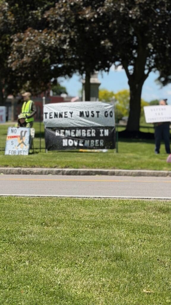 Protest signs reading 'Tenney Must Go' on lawn