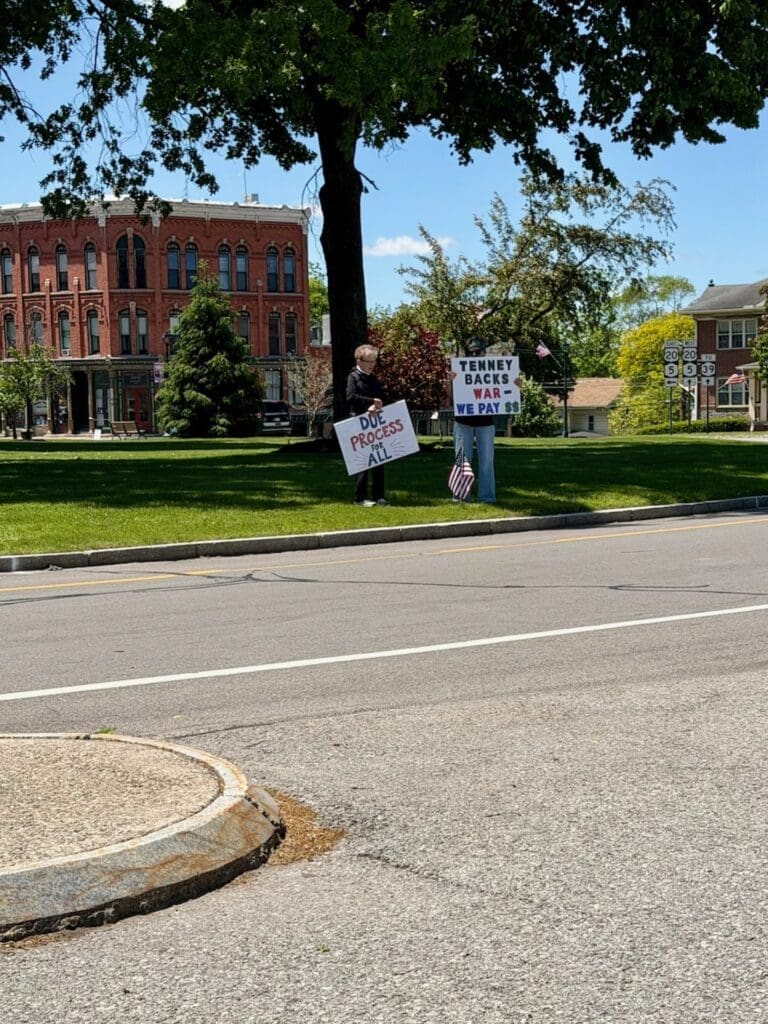 Two people holding protest signs in town square
