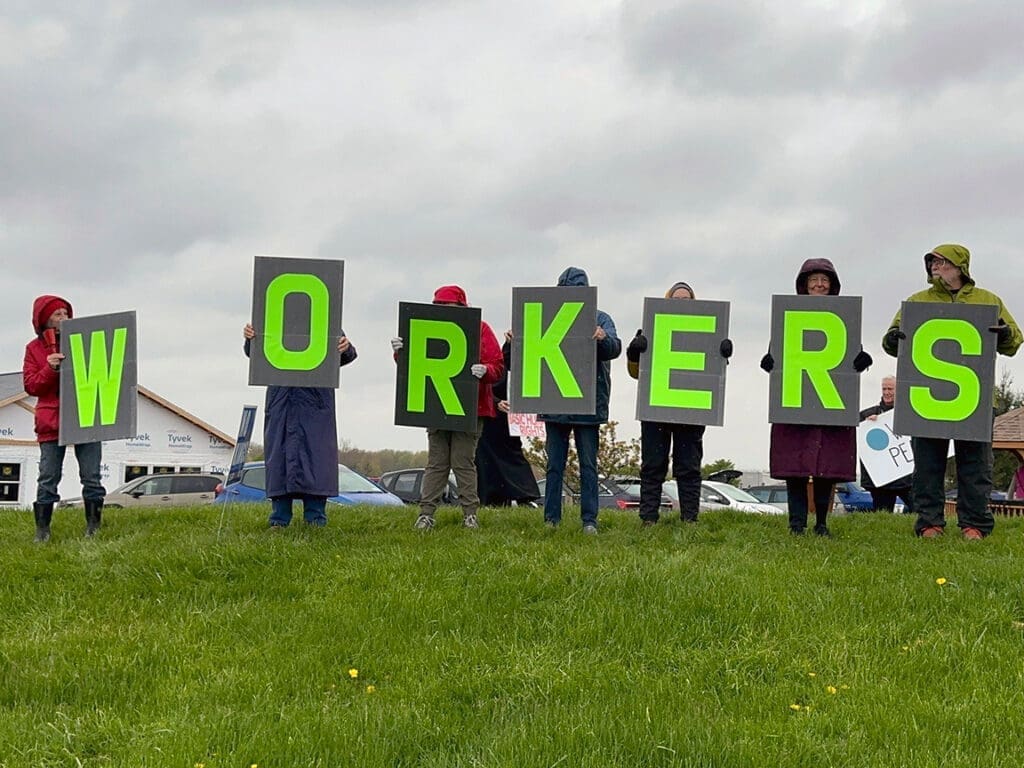 People holding signs spelling WORKERS outdoors