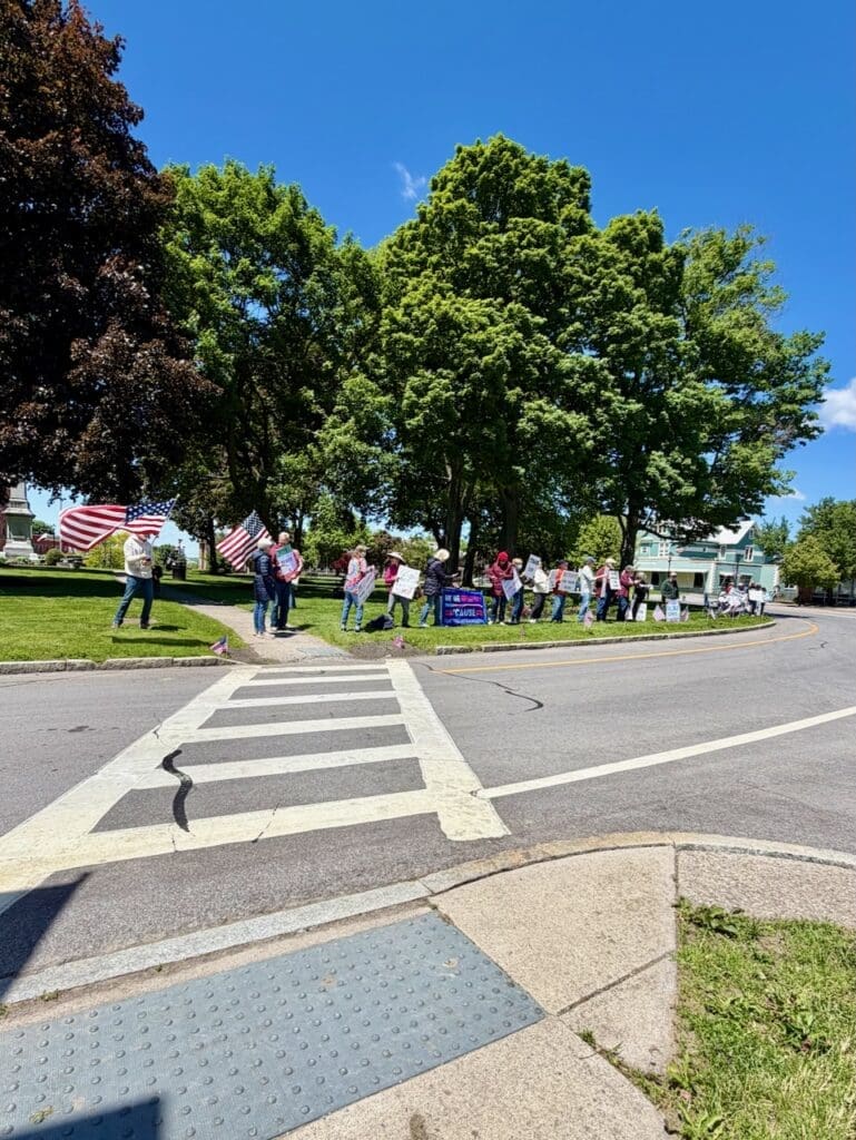 Protesters with American flags on sunny street corner