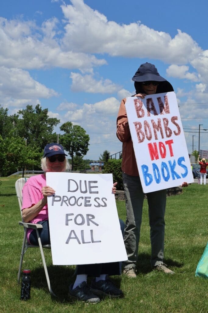 Two protesters holding signs about due process and banning bombs