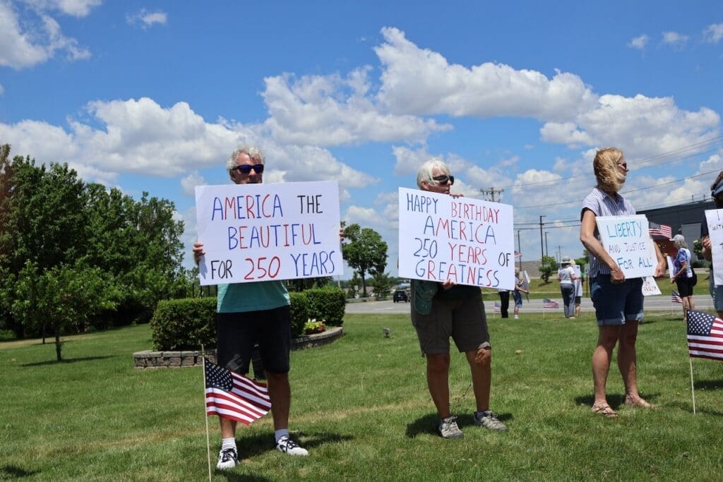 People holding patriotic signs celebrating America's 250th anniversary