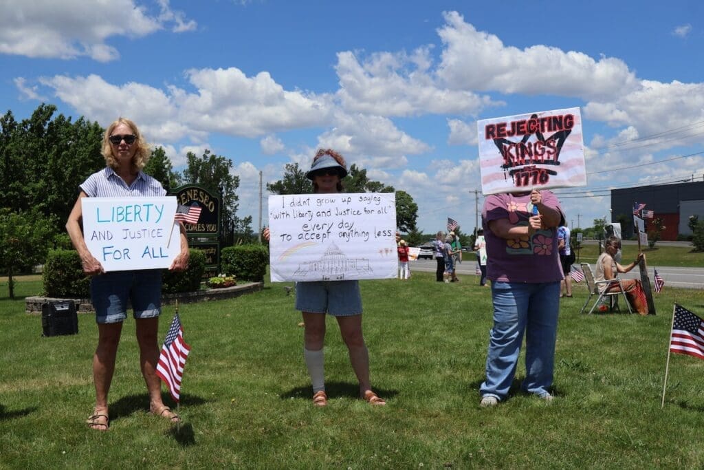 Three protesters holding liberty and justice signs outdoors