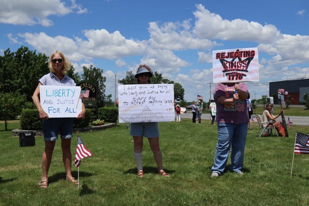 Three protesters holding signs about liberty and justice outdoors