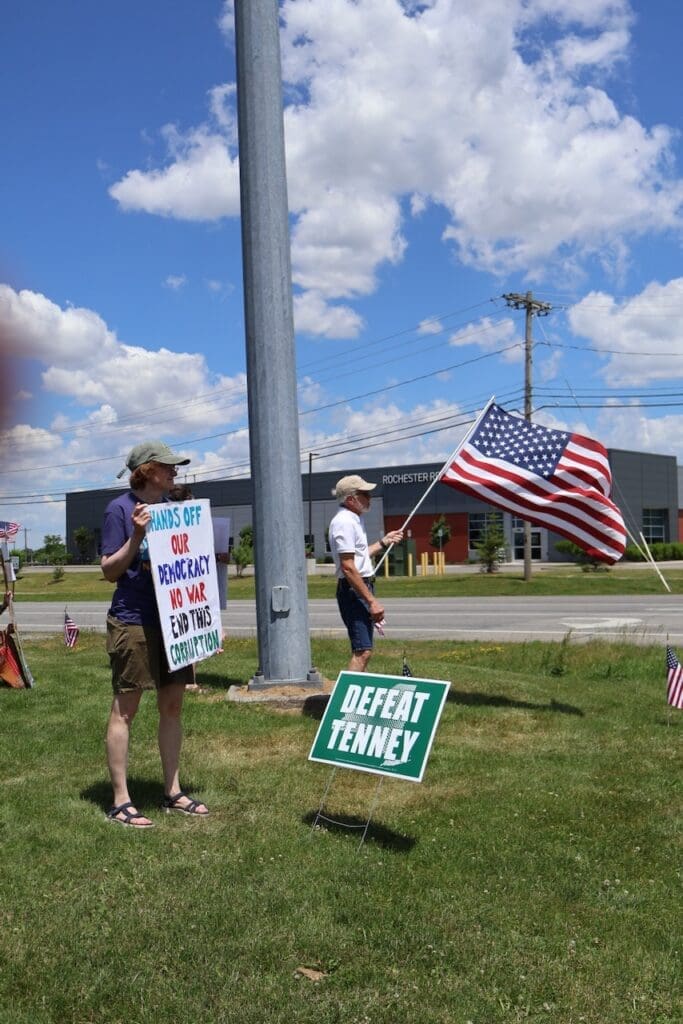 Protesters holding American flag and democracy sign outdoors