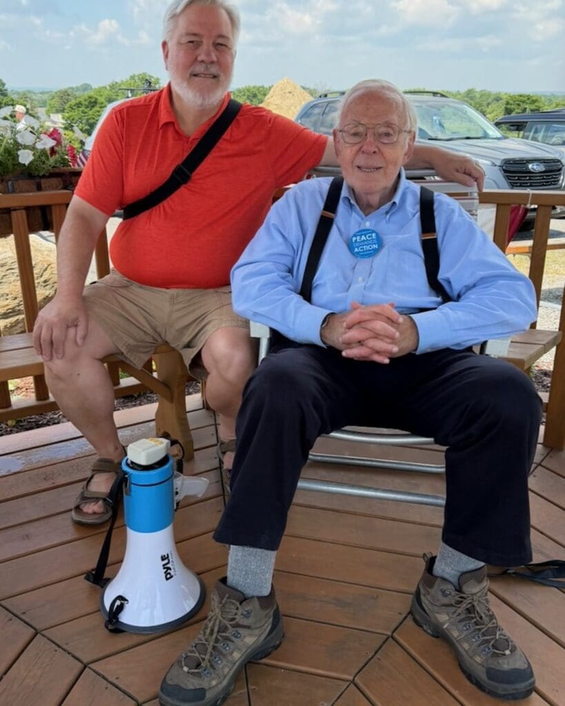 Two men sitting outdoors on a deck with a megaphone