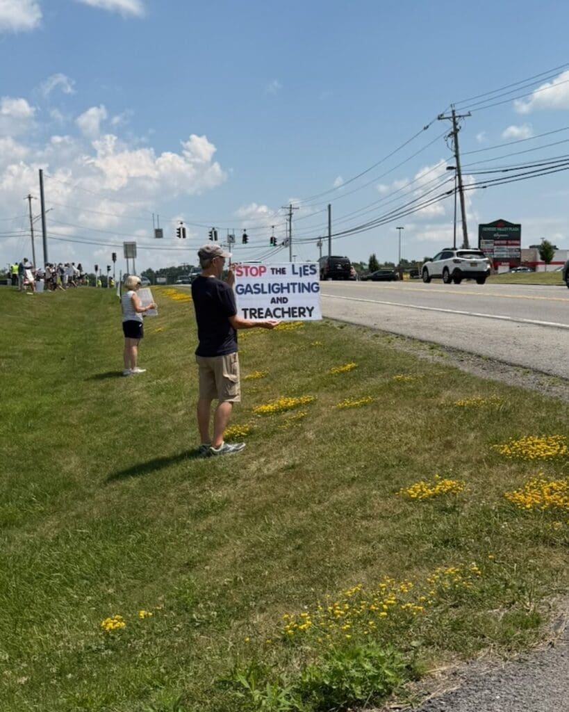 Protester holding sign reading Stop the Lies Gaslighting and Treachery