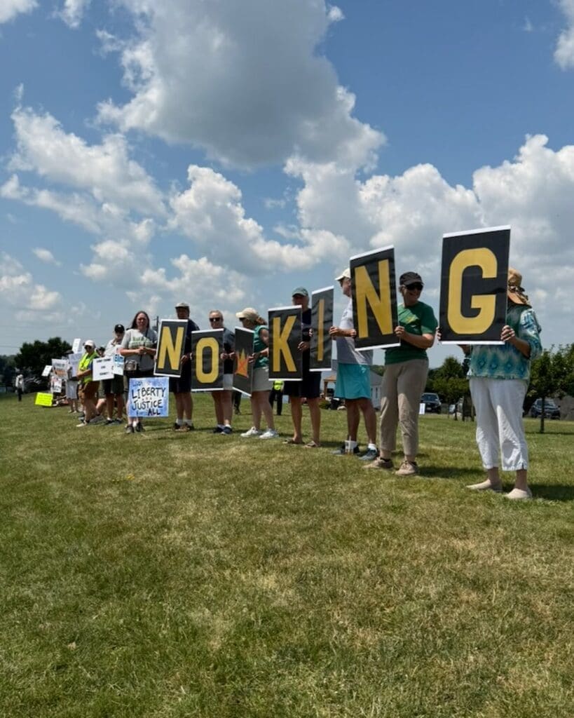 Protesters holding signs spelling No King outdoors