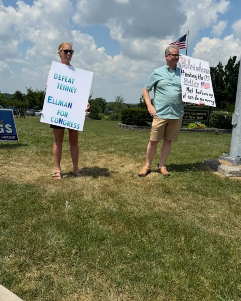 Two protesters holding political signs supporting Ellman for Congress