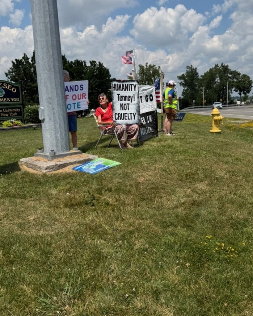 Protesters holding signs reading Humanity Not Cruelty roadside