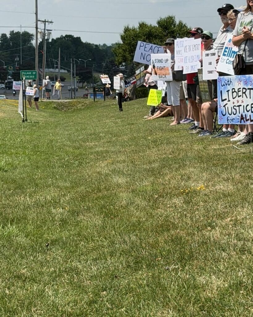 Protesters holding political signs along a roadside in Geneseo