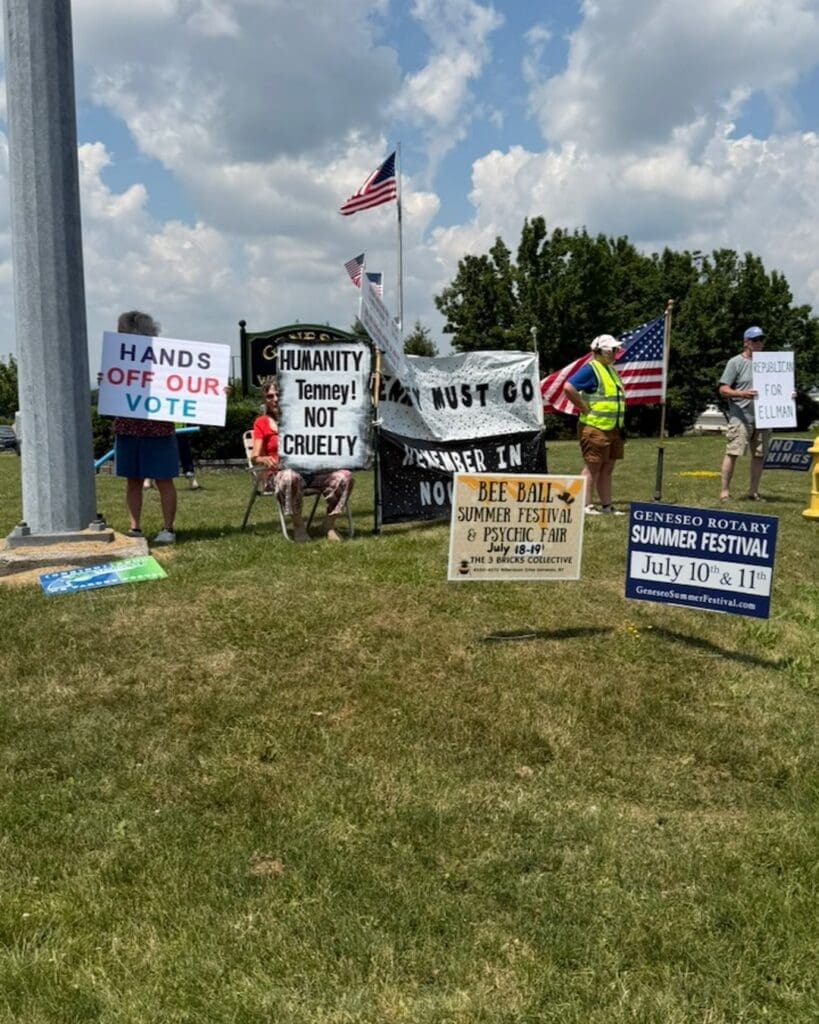 Protesters holding political signs at Geneseo outdoor rally