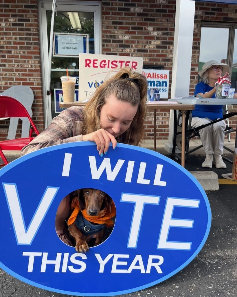 Woman and dachshund posing with I Will Vote sign