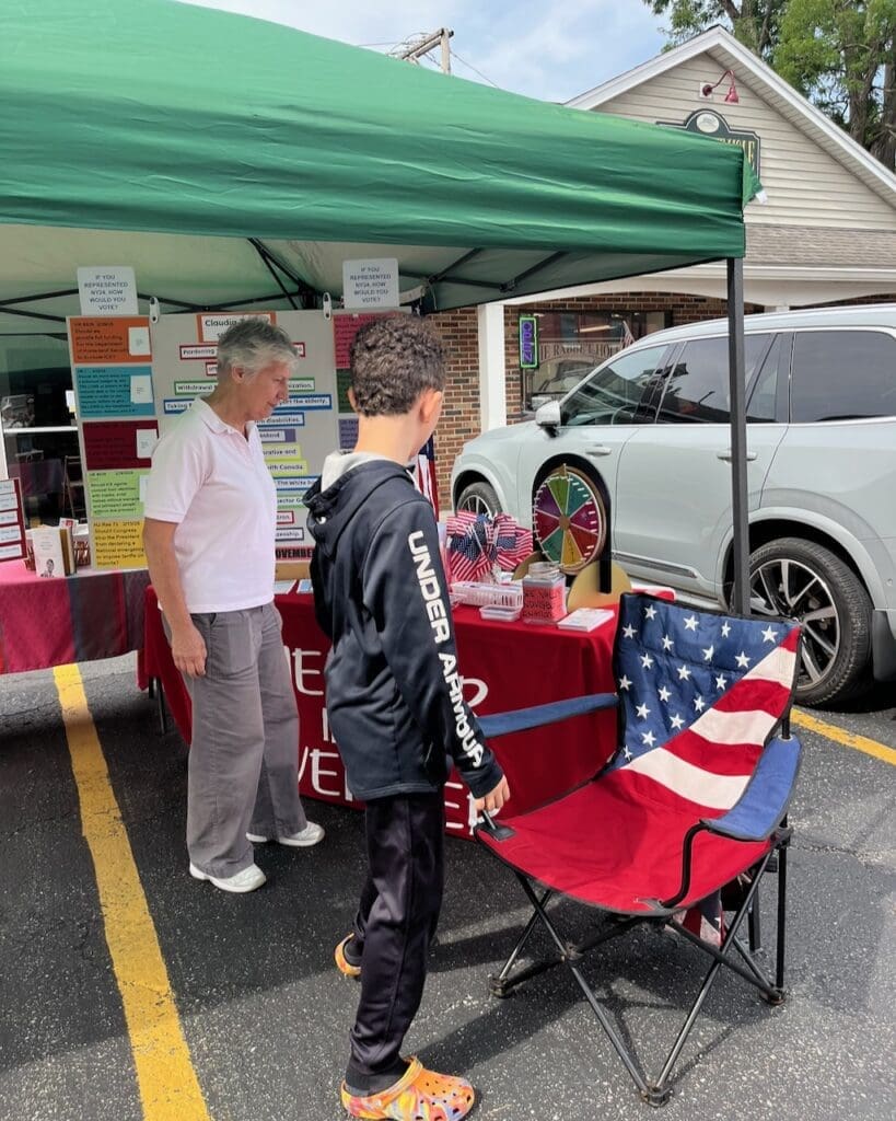 Two people at outdoor political information booth with American flags