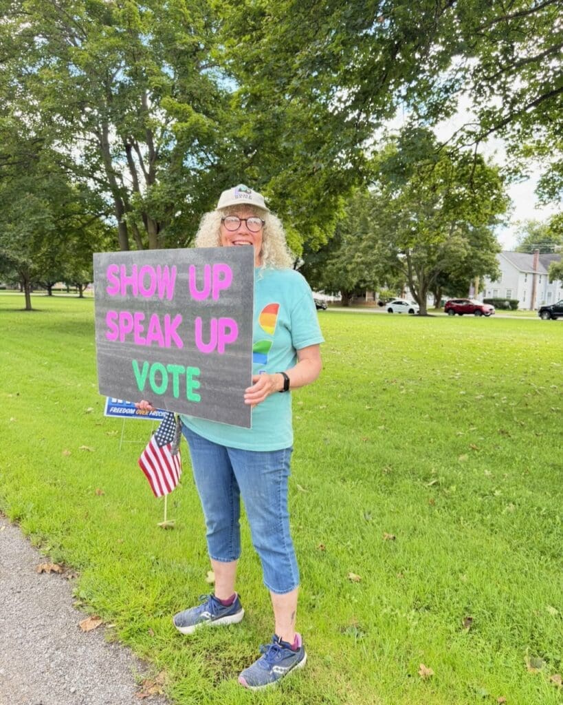 Woman holding Show Up Speak Up Vote sign outdoors