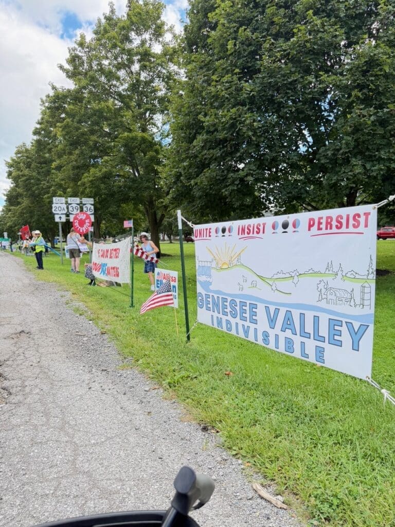Genesee Valley Indivisible rally with protest signs along roadside